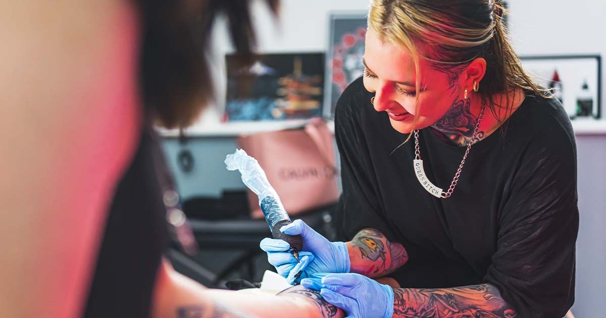 Female tattoo artist tattooing client.