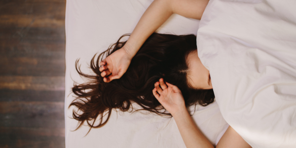 Top view of woman sleeping with blanket covering face.