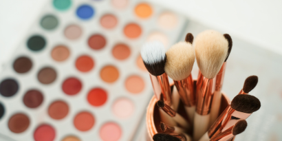 Makeup brushes with eyeshadow palette in background